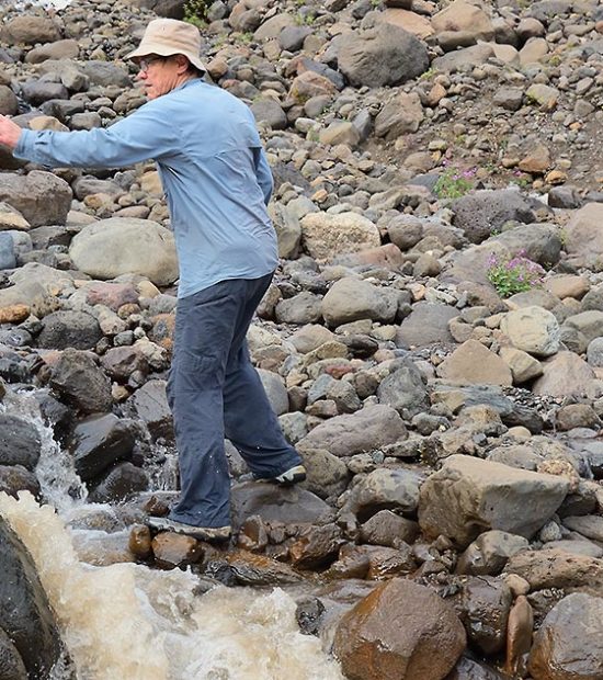 backpackers crossing a river in Alaska.