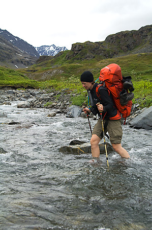 Backpacker safely crossing a creek in Wrangell-St. Elias National Park and Preserve, Alaska.