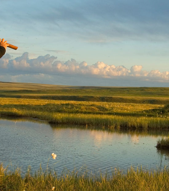 ANWR trips Hiker playing American Native flute on coastal plain Arctic National Wildlife Refuge, Alaska.