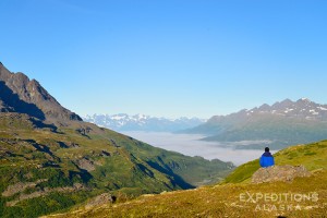 Bremner Mines to Tebay Lakes Hike; the heart of the Chugach Mountains A hiker rests on a rock and looks out over the Little Bremner, Bremner and Copper River valleys. The Chugach Mountains are something else! Wrangell - St. Elias National Park and Preserve.