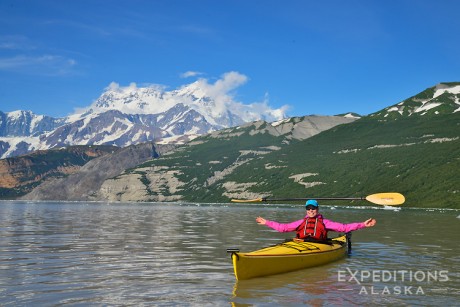 A photo of a young woman balancing a sea kayak paddle on her head, while sea kayaking in Icy Bay. Paddling under the world's highest coastal mountain, the person is sea kayaking in Taan Fjord. Sea kayaking in Icy Bay, Wrangell - St. Elias National Park and Preserve, Alaska.