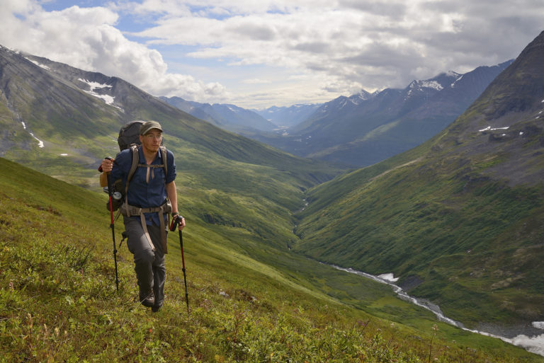 Hiking up Harry's Gulch in the eastern Chugach Mountains, a backpacker takes in the Southern Traverse on the Bremner Mines to Tebay Lakes trek, in Wrangell-St. Elias National Park, Alaska.