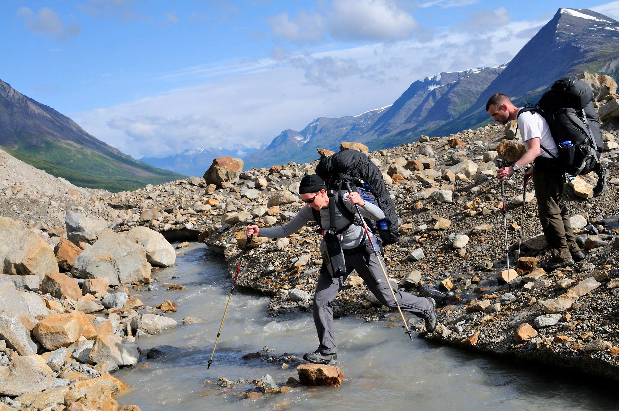 Backpackers crossing a stream on a glacier.