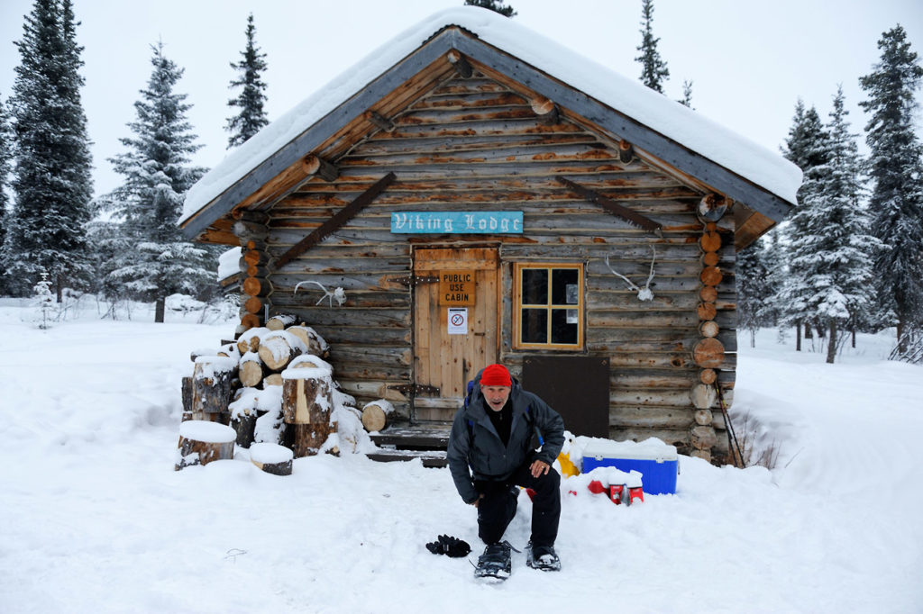 Alaska snowshoeing trip Putting on snowshoe at Viking Lodge Cabin for Alaska snowshoe trip. Wrangell-St. Elias National Park.