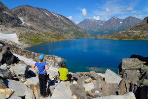 Camping and hiking trip in Alaska Hikers view an alpine tarn near Iceberg Lake, Wrangell-St. Elias National Park.