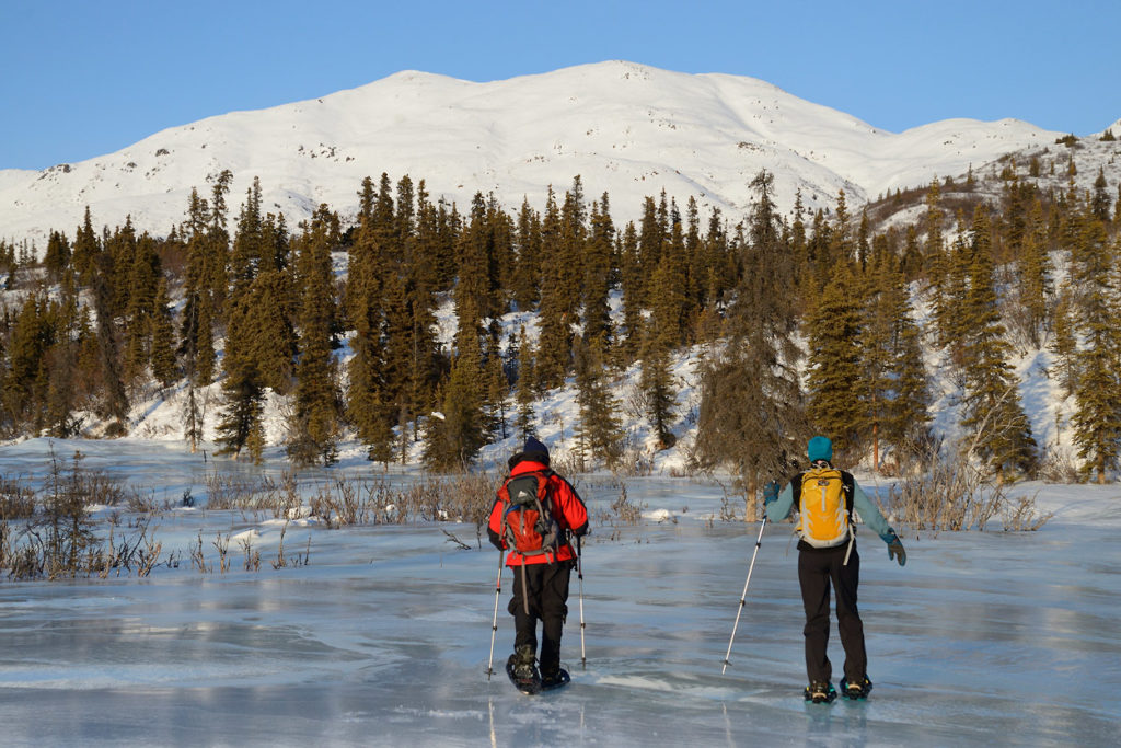 Alaska snowshoeing trip Snowshoers hiking on overflow, Caribou Creek, Wrangell-St. Elias National Park, Alaska.