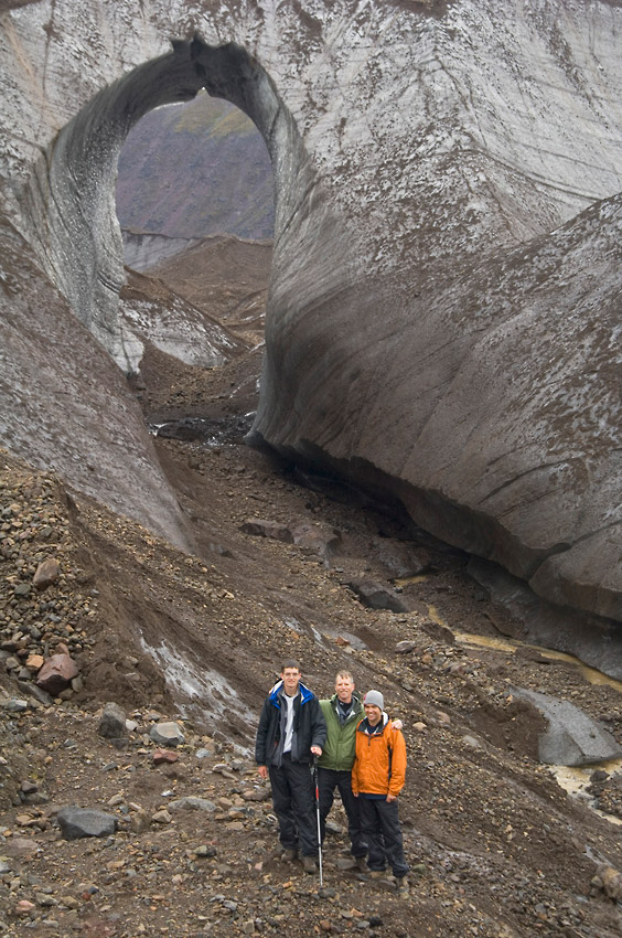 Hikers beneath glacial arch Sanford Glacier hiking trip Wrangell-St. Elias National Park, Alaska.