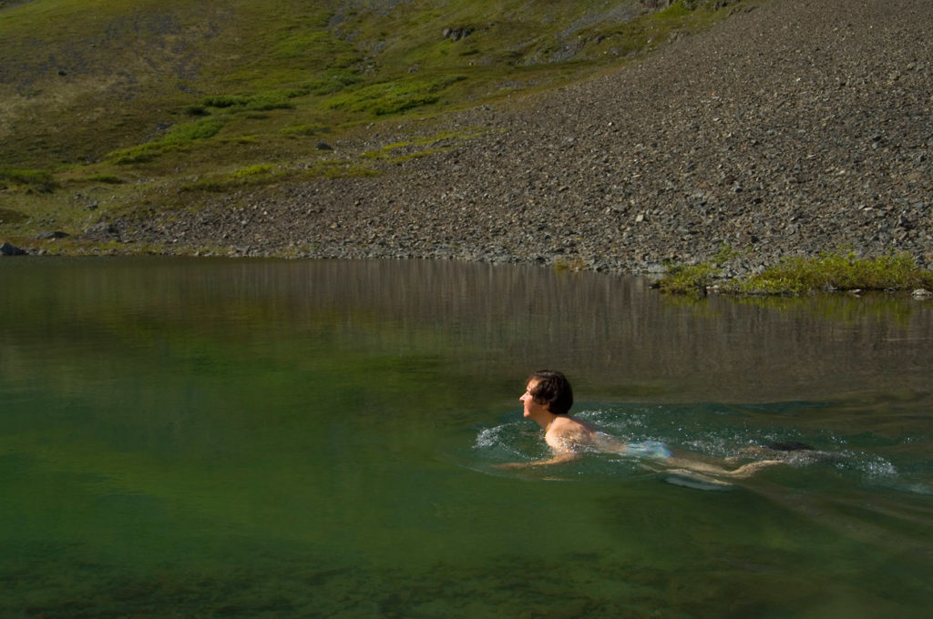 Backpacker taking a swim on the Southern traverse Route backpacking trip in Wrangell-St. Elias National Park, Alaska.