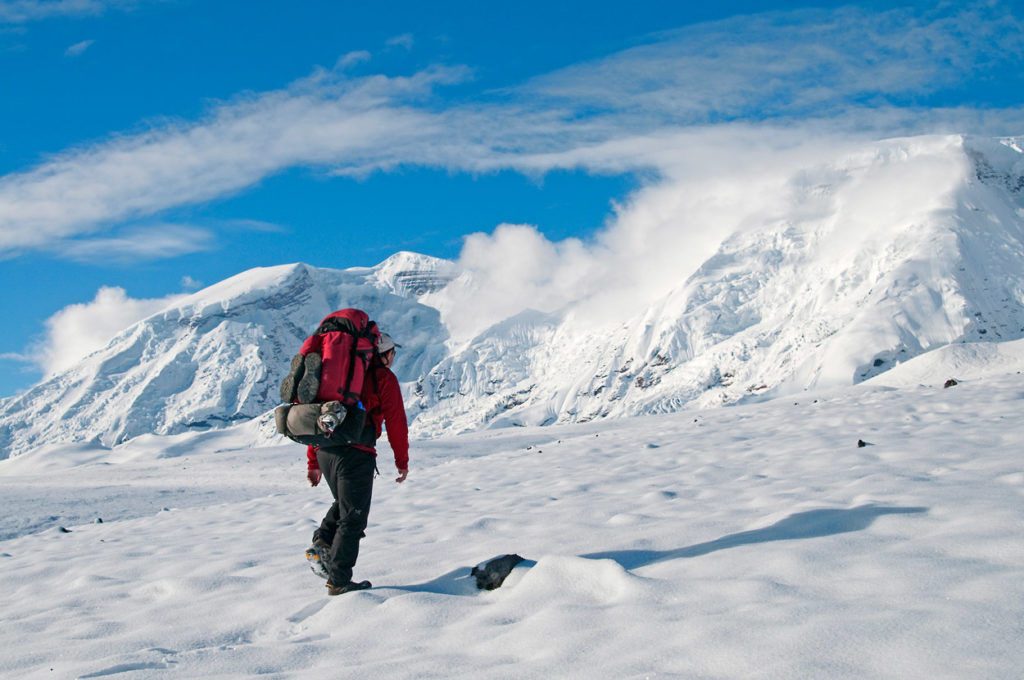 Hiking through fresh snow on Jarvis Plateau in Wrangell-St. Elias National Park backpacking trip, Alaska.