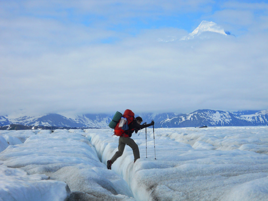 Malaspina Glacier backpacking trip Backpacker stepping over small crevasse on Malaspina Glacier backpacking trip, Wrangell-St. Elias National Park, Alaska.