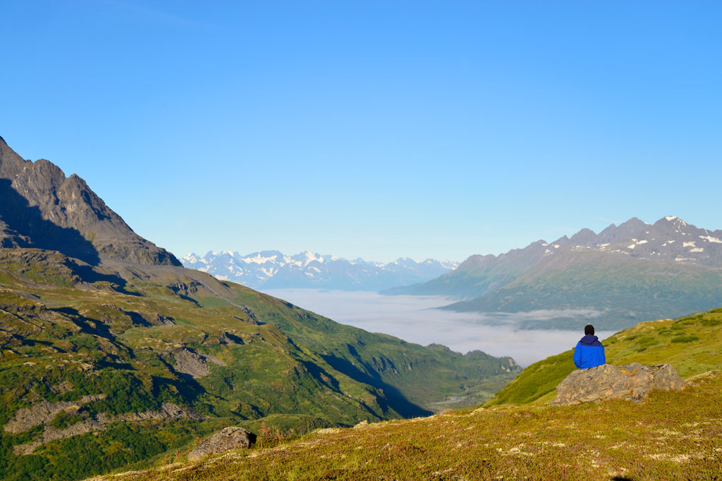 Backpacker looking over Little Bremner valley and heavy fog on Southern traverse backpacking trip, Wrangell-St. Elias National Park, Alaska.