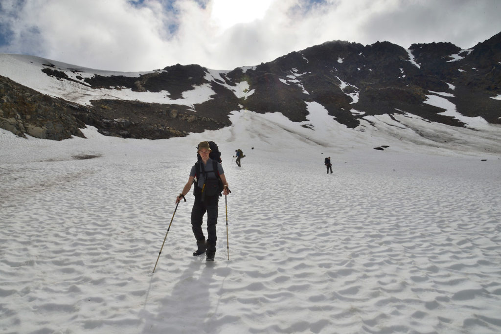 Hiking over snowfield Wrangell-St. Elias National Park backpacking trip Alaska.