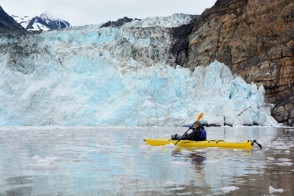 Alaska sea kayaking trip Icy Bay sea kayaker paddling near Taan Fjord on icy Bay Sea kayaking trip in Wrangell-St. Elias National Park, Alaska.