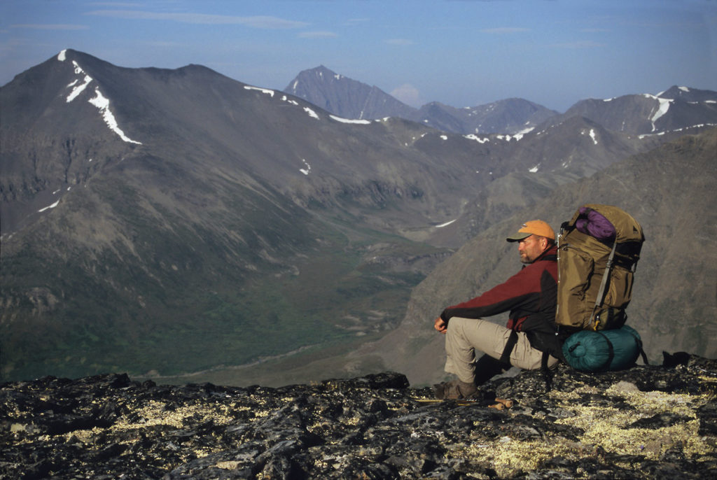 Hiker takes a break backpacking Seven Pass Route, Wrangell-St. Elias National Park, Alaska.
