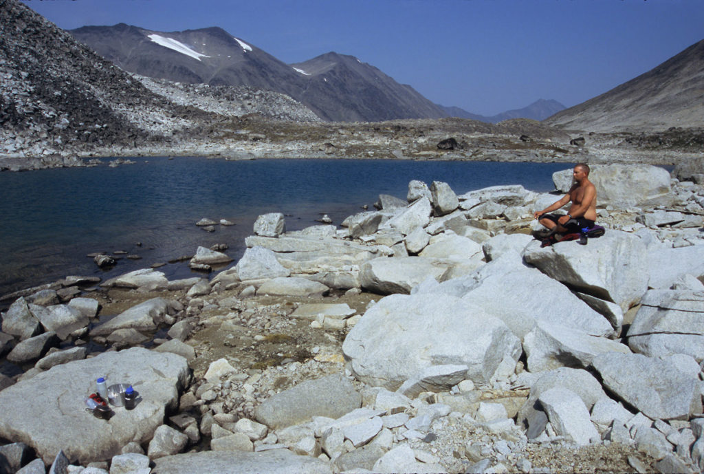 Backpacker meditating at alpine camp on Seven Pass Route, Wrangell-St. Elias National Park, Alaska.