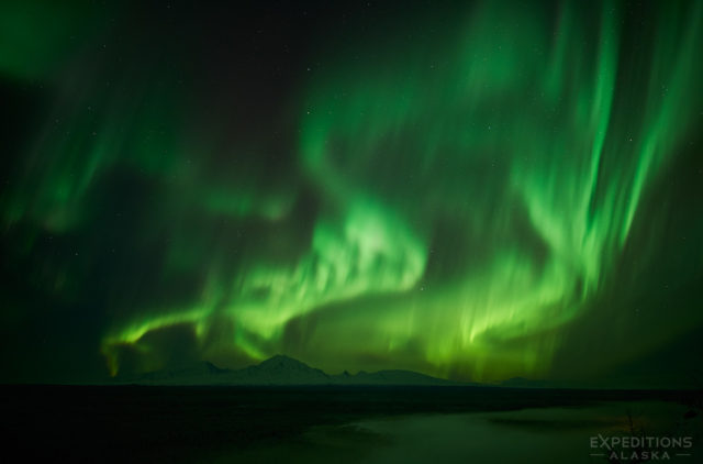 The Northern lights brighten the night sky over Wrangell Mountains. Wrangell - St. Elias National Park, Alaska.
