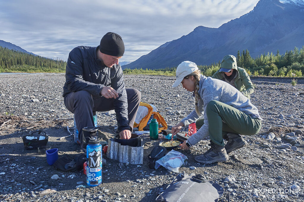 Group of packrafters cooking food on packrafting trip on the Koyukuk River, Gates of the Arctic National Park.