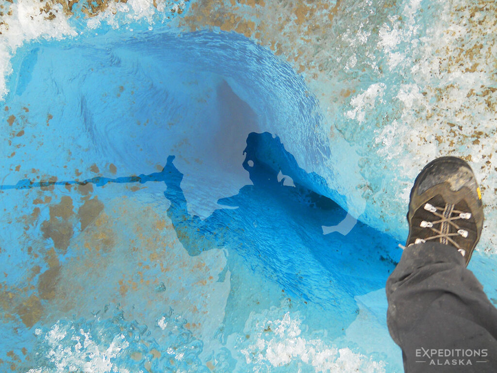Backpacking over a small pool on Malaspina Glacier in Wrangell-St. Elias National Park.
